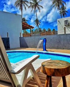 uma piscina com uma cadeira e uma fonte de água em Villa Madu Milagres à 300 metros da praia em São Miguel dos Milagres