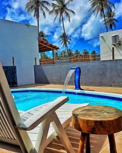 einen Stuhl neben einem Pool mit einem Brunnen in der Unterkunft Villa Madu Milagres à 300 metros da praia in São Miguel dos Milagres