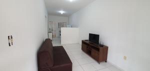 a living room with a couch and a television at Casa Temporada Guriri Pôr do Sol in São Mateus