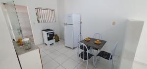 a kitchen with a table and a white refrigerator at Casa Temporada Guriri Pôr do Sol in São Mateus
