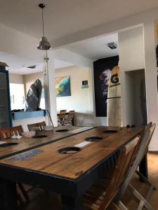 uma grande mesa de madeira num quarto com uma prancha de surf na parede em La Maquinita Hostel em Mar del Plata