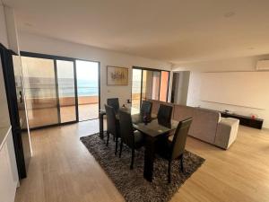 ein Wohnzimmer mit einem Tisch, Stühlen und einem Sofa in der Unterkunft Ocean Mirror Apartment in Praia