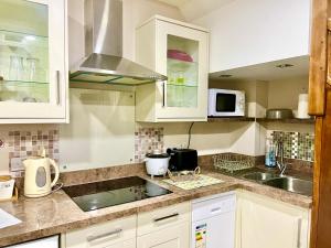 a kitchen with white cabinets and a sink at Ar-Rahman, 1 bed room and 1 Living room apartment in Kent