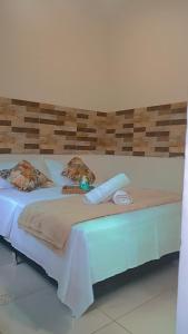 a large white bed with a wooden head board at Guest House Flor de Laranjeira in São Pedro da Aldeia