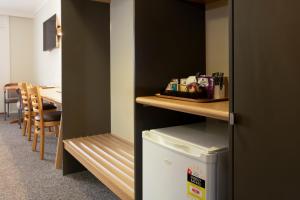 a room with a refrigerator and a table and chairs at Posthouse Motor Lodge in Goulburn
