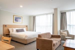 a hotel room with a bed and a couch at Posthouse Motor Lodge in Goulburn