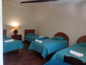 a room with three beds with blue sheets at Casa de Mama Valle - Urubamba in Urubamba