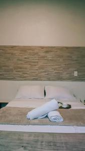 uma cama branca com almofadas brancas e uma cabeceira em madeira em Guest House Flor de Laranjeira em São Pedro da Aldeia