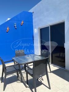 a table and chairs on a balcony with a blue wall at Diamante Dos Joyas Del Mar Bahia de Kino in Bahía Kino