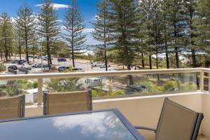 a balcony with a table and chairs and trees at Ambassador Beachfront Apartments - Hosted by Burleigh Letting in Gold Coast