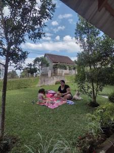 Una donna e un bambino seduti su una coperta nell'erba di GartenHaus a São Bento do Sul