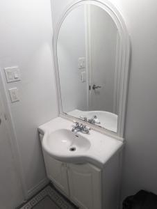 bagno bianco con lavandino e specchio di Home of Pleasantness a Hamilton