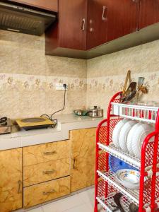 una cocina con un estante rojo con platos. en Asma-ul-husna apartment, en Rājshāhi