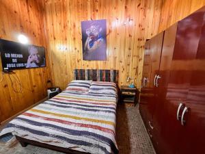 sypialnia z łóżkiem w drewnianej ścianie w obiekcie Departamento D w mieście Coihaique