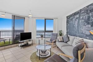 a living room with a couch and a tv at Seascape - Hosted by Burleigh Letting in Gold Coast