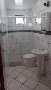 a white tiled bathroom with a toilet and a sink at Apartamento Dante Tomio in Balneário Camboriú