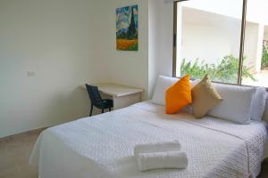 モンテリアにあるMagico Apartaestudio con Piscina 1 Habitacion PR56Aのベッドルーム1室(白いベッド1台、オレンジと黄色の枕付)