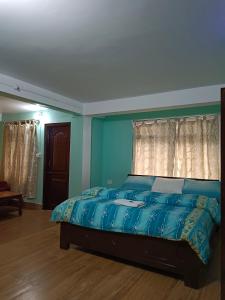 a bedroom with a bed with a blue comforter at Hotel PineWood Tawang in Tawang