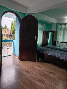 ein Schlafzimmer mit einem Bett und einer offenen Tür in der Unterkunft Hotel PineWood Tawang in Tawang