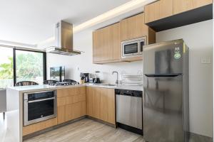 a kitchen with stainless steel appliances and wooden cabinets at Lumina at Cardinal San José del Cabo in San José del Cabo