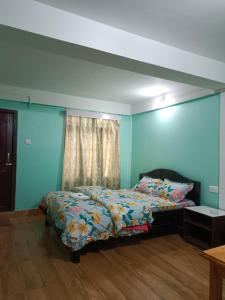 Schlafzimmer mit einem Bett mit blauen Wänden und einem Fenster in der Unterkunft Hotel PineWood Tawang in Tawang