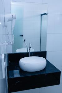 a bathroom with a white sink on a black counter at Hotel e Motel Madrugada in Itu