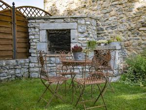 een tafel en stoelen voor een stenen muur bij Charming cottage in Gimn e in Doische