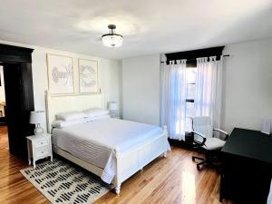 Schlafzimmer mit einem weißen Bett und einem Schreibtisch in der Unterkunft Host your group - West End Sea Captain Home in Portland