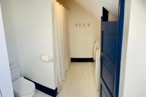ein kleines Bad mit einem WC und einer blauen Tür in der Unterkunft Host your group - West End Sea Captain Home in Portland