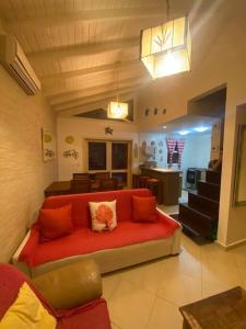 uma sala de estar com um sofá vermelho e uma cozinha em Esplendor House - Little Cambury em São Sebastião