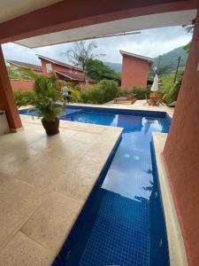 a blue swimming pool with a potted plant next to a house at Esplendor House - Little Cambury in São Sebastião