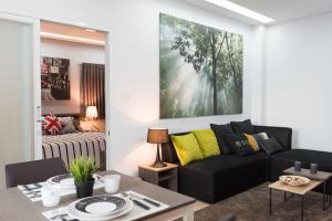 a living room with a black couch and a table at Zada Residence in Nakhon Ratchasima