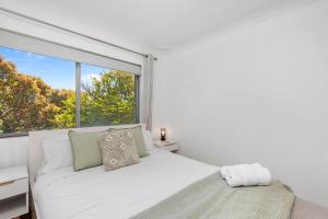 - une chambre avec un lit blanc et une grande fenêtre dans l'établissement 22 Superb Subiaco Apt For Couplesparkng, à Perth