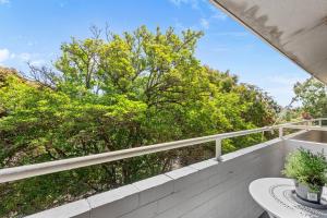 d'un balcon avec une table et une vue sur les arbres. dans l'établissement 22 Superb Subiaco Apt For Couplesparkng, à Perth