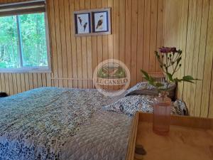 a bedroom with a bed and a table with a vase of flowers at Cabaña El Canelo in Puerto Varas