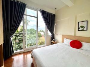 a bedroom with a large window and a bed with a red pillow at Hue Four Seasons Hotel in Hue