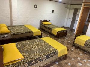 Habitación con 3 camas con sábanas amarillas. en Casa campestre Montenegro Quindio, en Montenegro