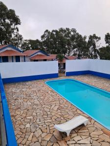 a resort swimming pool with a chair in front of it at Pousada Fazendinha Alto da Serra in Serra Negra