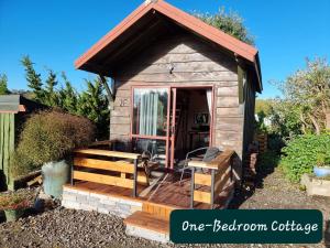 a small wooden dog house with a porch at Swiss-Kiwi Retreat A self-contained Appartment and a Tiny House option in Tauranga