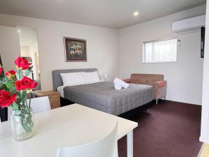 a bedroom with a bed and a table with roses at Morrinsville Motel in Morrinsville