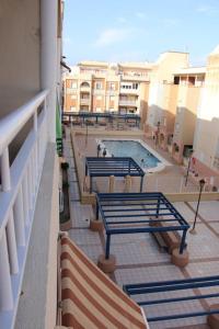 einen Balkon mit Bänken und einen Pool auf einem Gebäude in der Unterkunft Apartamento Buenavista Roquetas de Mar in Roquetas de Mar