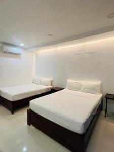2 letti in una piccola camera con pareti bianche di Samba Bluewater Resort a Olongapo