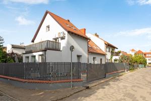 a white house with a fence on a street at Lion Apartments - Comfy Sopot Family House in Sopot