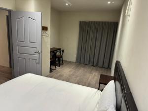 a bedroom with a bed and a table and a door at Saint Hostel in Beigang