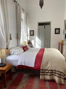 a bedroom with a large bed and a window at Riad le Consulat - Riad privé avec services in Essaouira