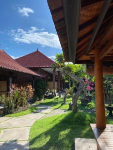 a garden with a house with a tree in the yard at Tebu menjangan homestay in Banyuwedang