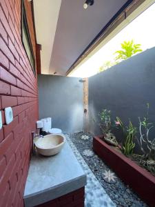 a bathroom with a bowl sink on a brick wall at Tebu menjangan homestay in Banyuwedang