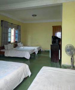 een hotelkamer met 3 bedden en een ventilator bij Hung Vuong Hotel in Pleiku
