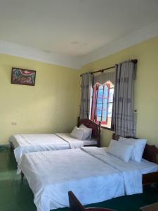two beds in a room with two windows at Hung Vuong Hotel in Pleiku