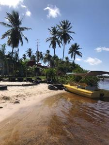 a yellow boat sitting on a beach with palm trees at Chalé recanto do sol in Santo Amaro